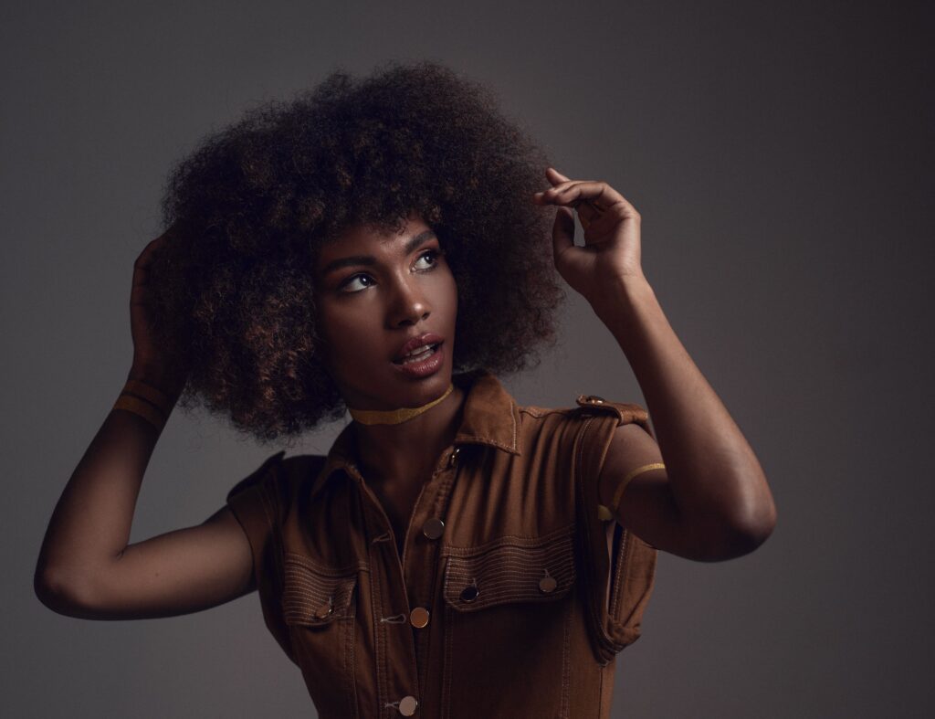 Studio portrait of a beautiful black woman with curly hair, showcasing fashion and elegance.